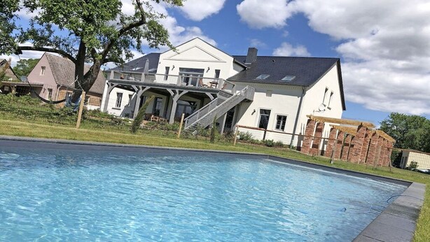 Uma piscina com uma casa ao fundo.