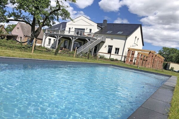 A swimming pool with a house in the background. - Erbschulzenhof (Müritz) 6 Pers. (Buchholz (Müritz))
