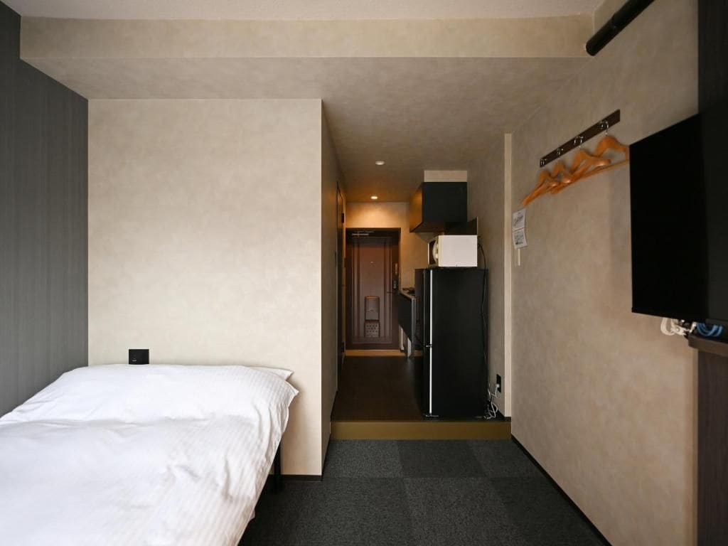 Una habitación de hotel con una cama, televisión y refrigerador.