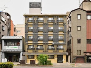 Un hotel de varios pisos con fachada moderna, que presenta una entrada destacada y señalización para 'Excellence Inn Nishihonganji'.