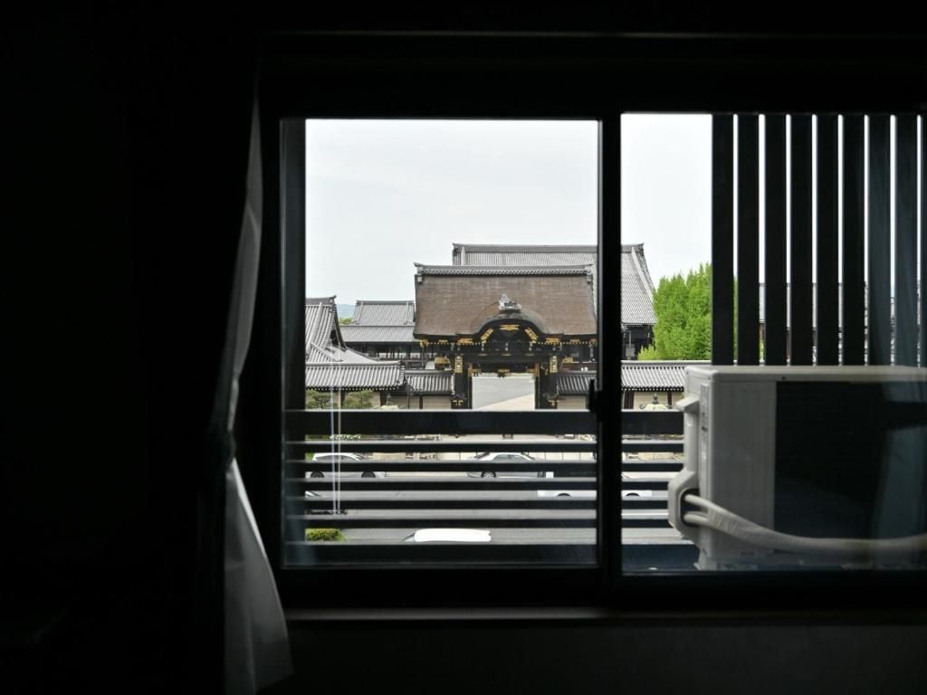 Une vue par la fenêtre sur une architecture traditionnelle, avec un bâtiment en arrière-plan.