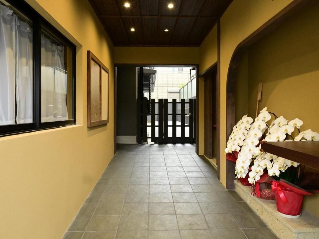 A corridor with a tiled floor, a wooden ceiling, and a door leading to an outdoor area.