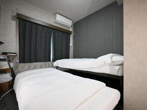 Habitación de hotel con dos camas, un escritorio y un equipo de aire acondicionado.