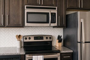 A kitchen with a microwave, stove, and refrigerator. - Boulevard Stays Modern Midtown 1BR Pool, Gym & Parking 06 (Nashville)