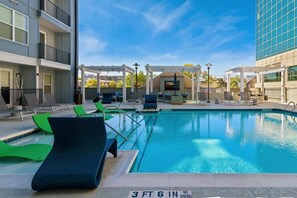 A swimming pool with lounge chairs, a pergola, and a view of a modern building. - Boulevard Stays Modern Midtown 1BR Pool, Gym & Parking 06 (Nashville)