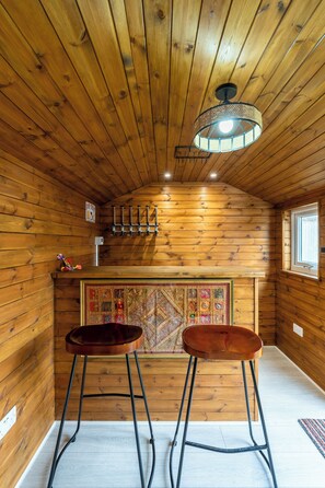 A wooden interior with a sloped ceiling, a hanging light fixture, a bar area with stools, and a decorative wall panel. - 4 bedroom home in Croydon (Croydon)