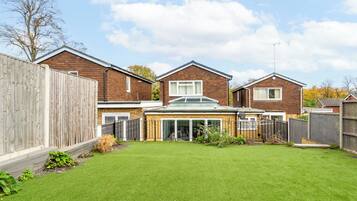 A residential area with three houses, a fenced backyard, and a clear sky.