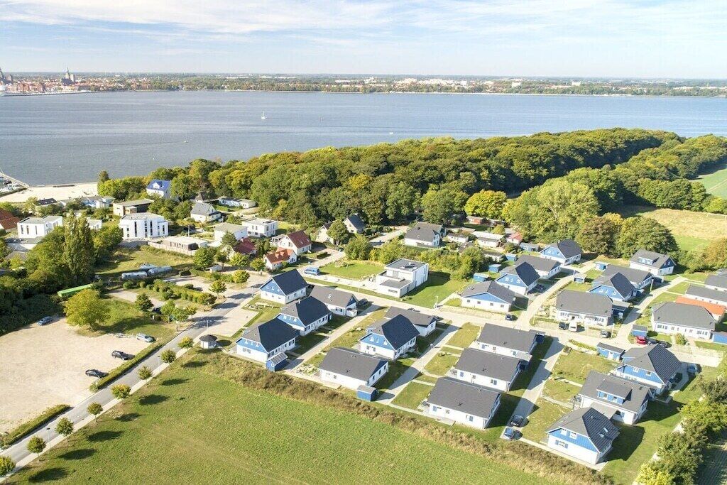 A residential area with houses arranged in a grid pattern, a body of water in the background, and a distant city skyline.