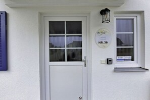 A white door with a window, a wall-mounted sign, and a small shelf with a window above it. - Holiday home in Altefähr with swimming pool (Altefähr)