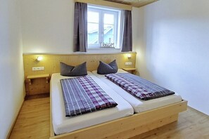 A double bed with a headboard, two bedside tables, a window with curtains, and a wooden floor. - Holiday home in Altefähr with swimming pool (Altefähr)