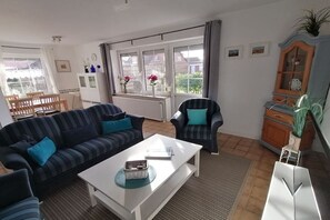 A living room with a sofa, armchair, coffee table, and a cabinet. - Holiday apartment with 2 bedrooms (Norden-Norddeich)