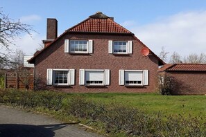 A brick house with a red-tiled roof, white shutters, and a chimney. - Holiday apartment with 2 bedrooms (Norden-Norddeich)