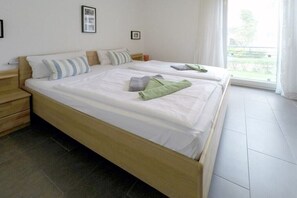 Ein Doppelbett mit Holzbettgestell, zwei Kissen und ein grünes Handtuch.