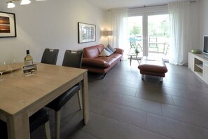 Ein modernes Wohnzimmer mit einer Couch, einem Esstisch und einem Fernseher.