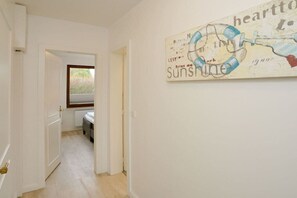 A hallway with a door leading to a room, a window, and a wall with a graphic. - Holiday apartment with 1 bedroom (Westerland\/ Sylt)