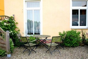 A patio with a table and chairs, a wooden gate, and a window with a white frame. - Holiday apartment in Waren with swimming pool (Waren)