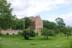 A large building with a symmetrical facade, surrounded by a well-maintained lawn and trees. - Holiday apartment in Waren with swimming pool (Waren)