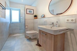 A modern bathroom with a toilet, sink, and mirror. - Holiday apartment with 2 bedrooms (St. Peter-Ording)
