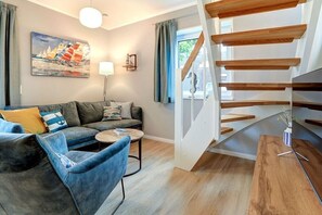 Ein modernes Wohnzimmer mit einer Couch, einem Couchtisch und einer Treppe mit Holzbeschlägen.