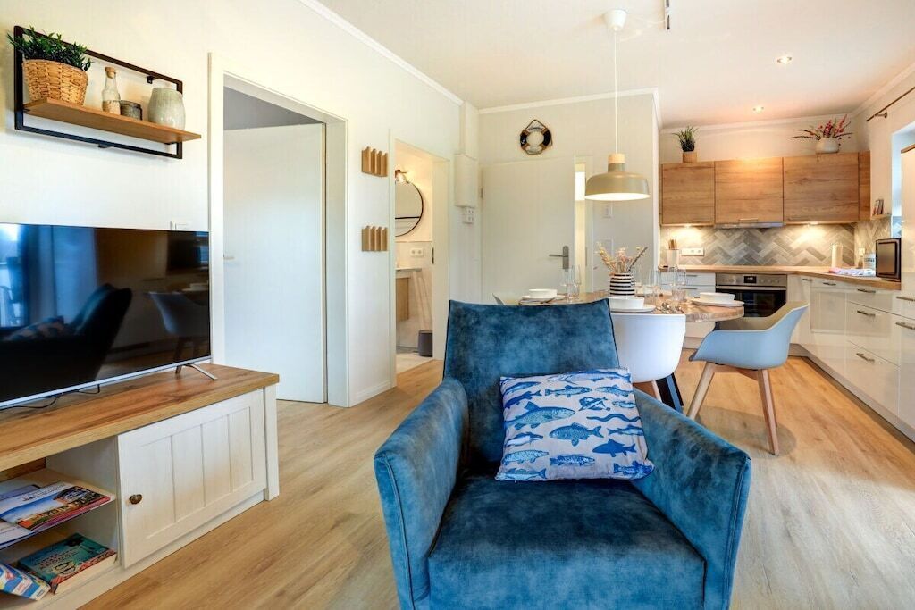 A modern living room with a blue armchair, a flat-screen TV, and a wooden entertainment unit.