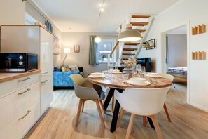A modern kitchen with a dining area, wooden cabinets, and a staircase. - Holiday apartment with 2 bedrooms (St. Peter-Ording)