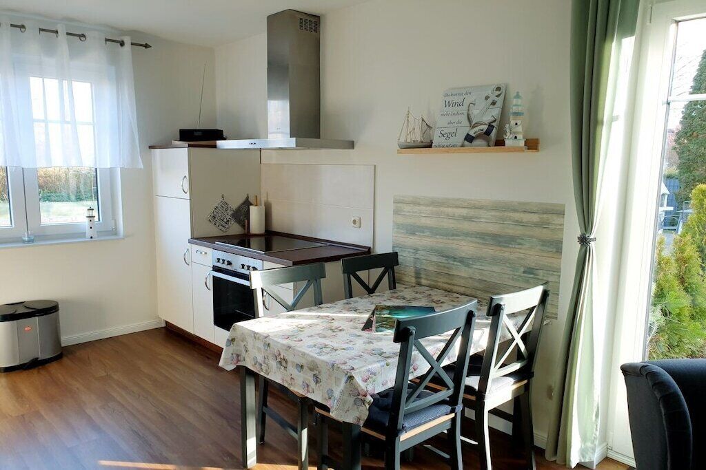 Una cocina compacta con una mesa de comedor, sillas y una ventana con cortinas.