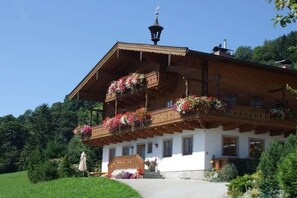 A traditional chalet with wooden balconies, a staircase leading to the entrance, and a clear sky. - Ebnerbauer Apartment 1 (Piesendorf)