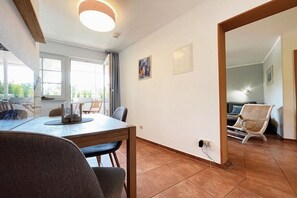 Ein Essbereich mit Tisch und Stühlen, ein Fenster mit Vorhängen und eine Wand mit einem Bild.