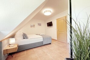 A bedroom with a bed, bedside table, lamp, and a television on the wall. - Holiday apartment with 2 bedrooms (Dierhagen)