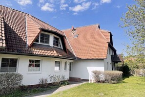 A two-story house with a sloped roof, white exterior walls, and a small front porch. - Holiday apartment with 2 bedrooms (Dierhagen)