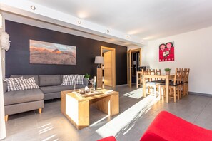 A modern living room with a sofa, coffee table, and a painting on the wall. - Gästehaus Osterthor - Ferienwohnung Asitz, Balkon & Bergblick (Saalfelden am Steinernen Meer)