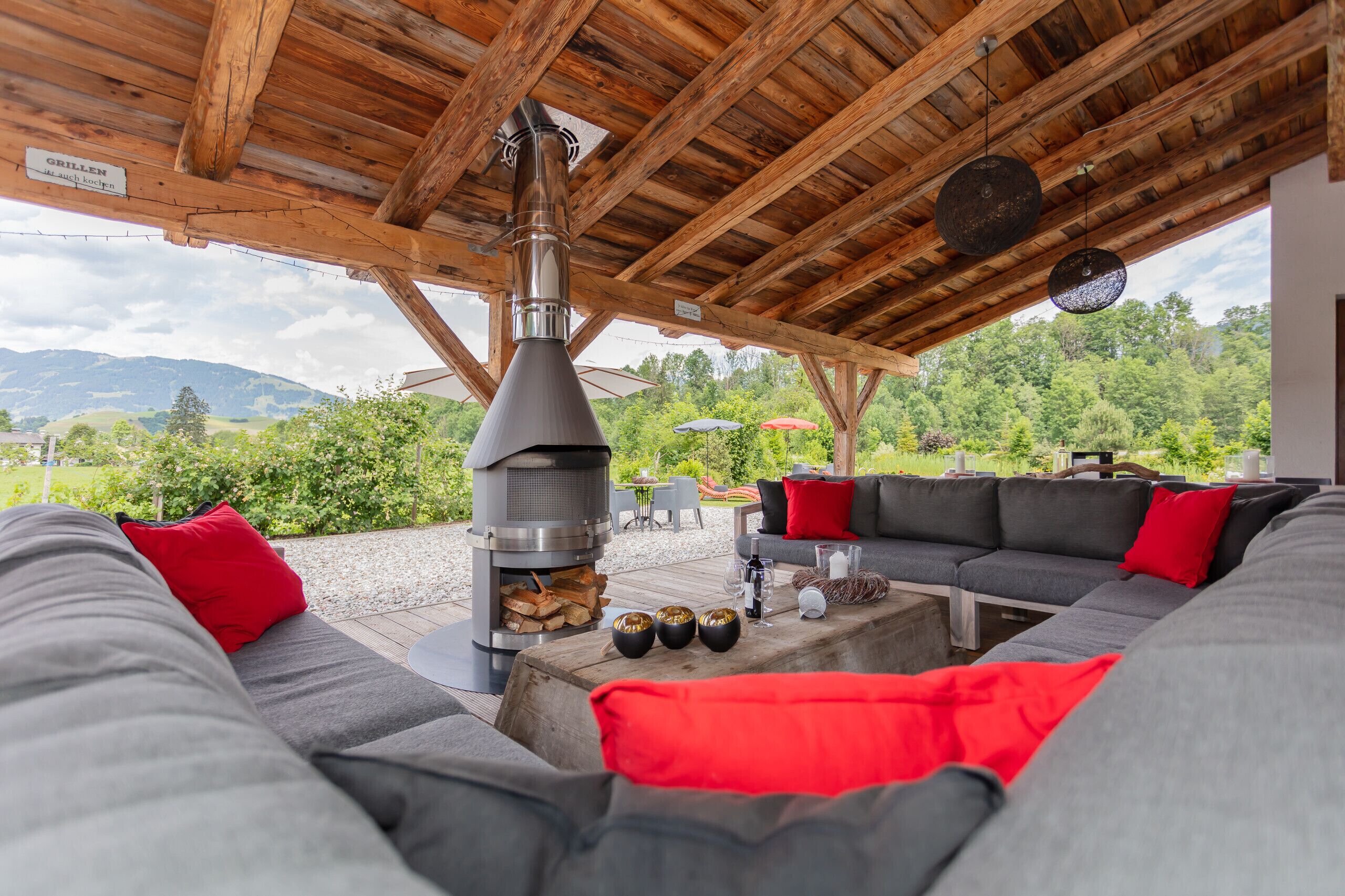 An outdoor seating area with a wood-burning stove, a sofa, and a view of the surrounding landscape.
