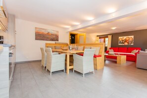 Ein modernes Wohnzimmer mit Essbereich, einem roten Sofa und einem Gemälde an der Wand.