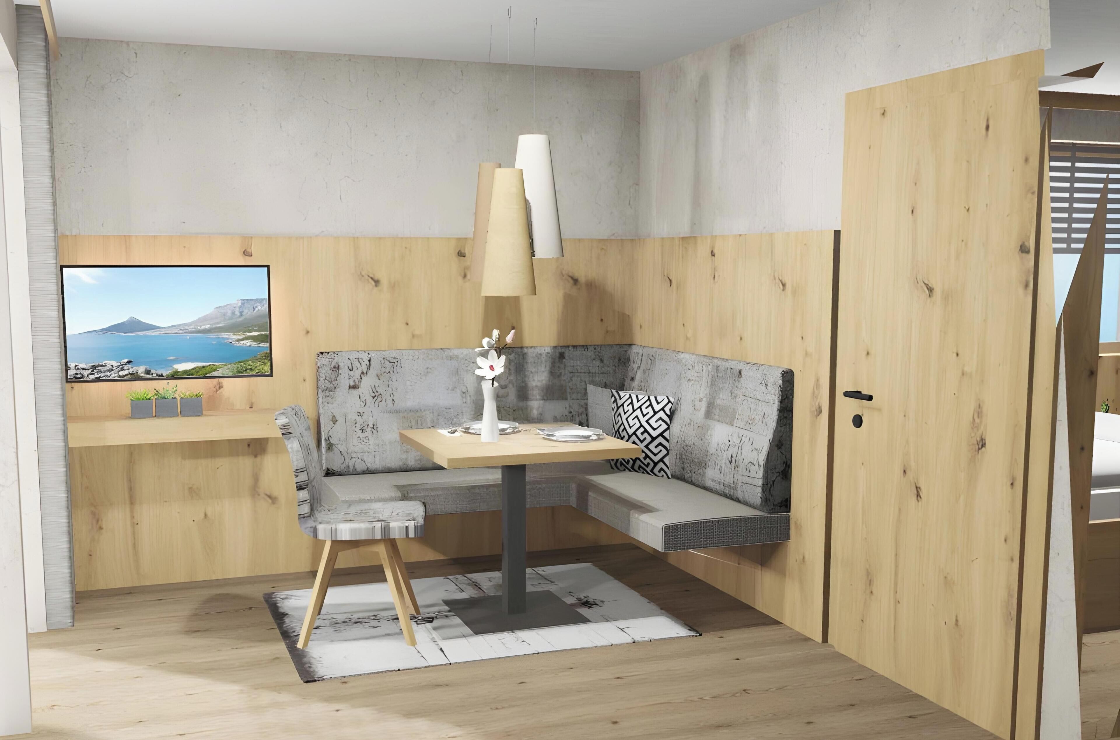 A compact room with a wooden floor, a sofa, a small table, a lamp, and a television displaying a scenic landscape.