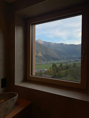 Ein Zimmer mit Fensterblick auf eine Berglandschaft.