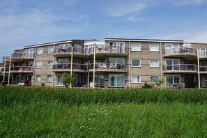 A multi-story residential building with balconies, large windows, and a grassy foreground. - Residence Juliana 52 (Julianadorp)