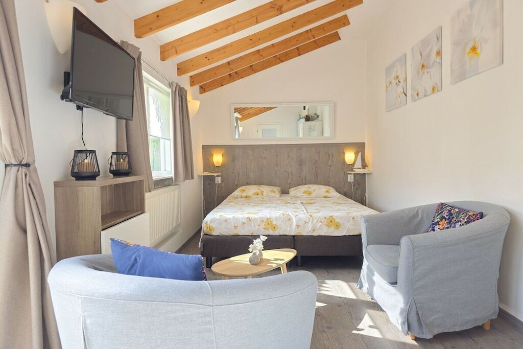 Quarto com cama, televisão, sofá e poltrona.
