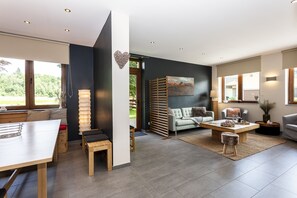 Ein modernes Wohnzimmer mit Sofa, Couchtisch und einem Essbereich mit Tisch und Stühlen.