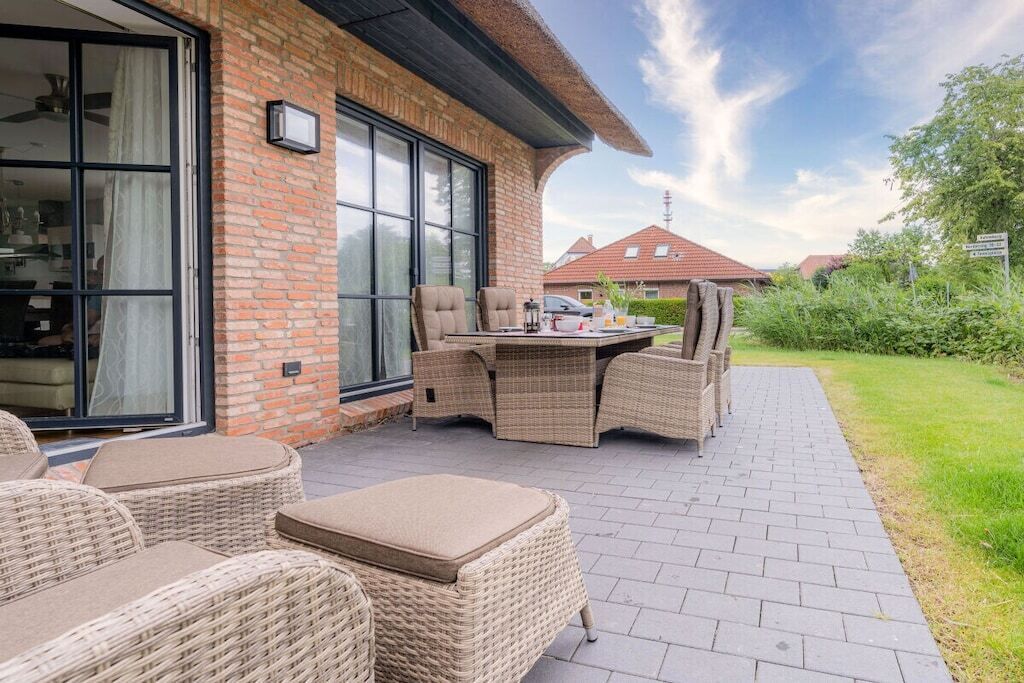 Une terrasse extérieure avec des meubles en osier et un mur en briques.