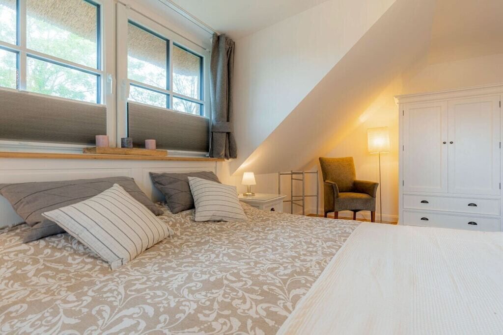 A bedroom with a large bed, a window, a chair, and a wardrobe.