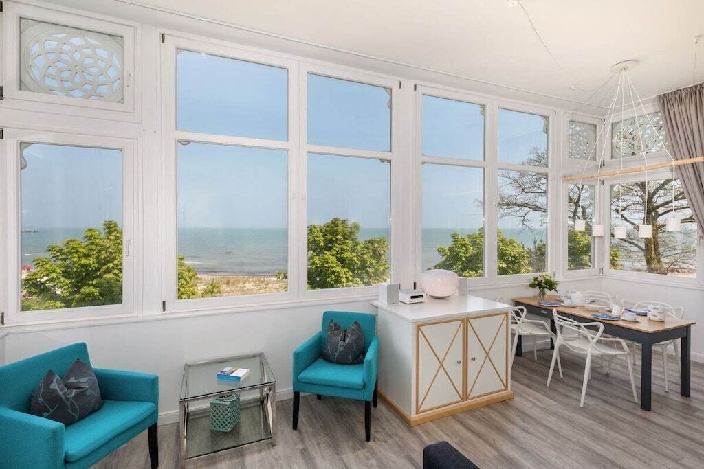 A room with large windows, a dining area, and a seating arrangement.