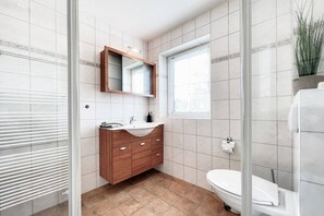 Un bagno con un mobile lavabo in legno, un lavandino bianco, uno specchio, un water e una finestra.