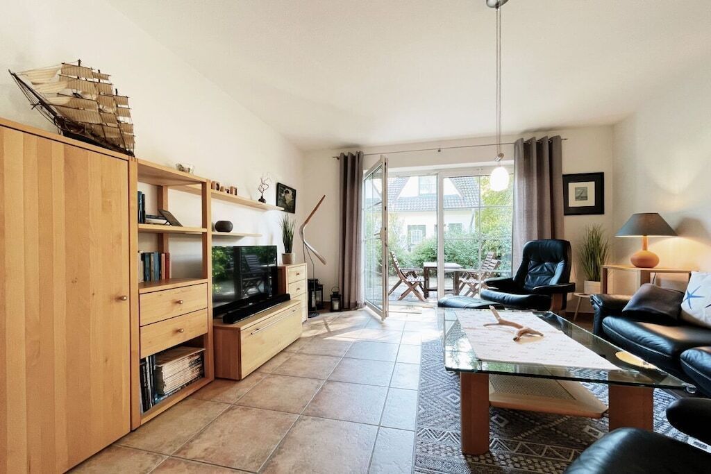 Ein Wohnzimmer mit Fernseher, Holzschrank und Glastisch.