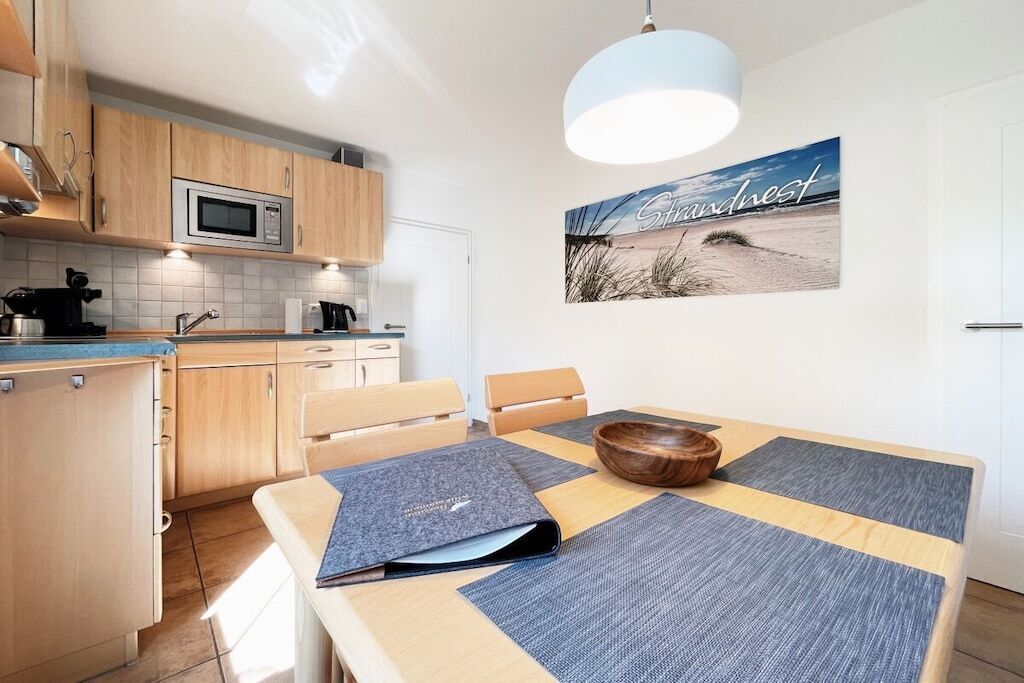 Une cuisine moderne avec des meubles en bois, un four à micro-ondes et un coin repas comprenant une table et des chaises.
