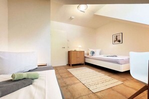 Ein Schlafzimmer mit einem Bett, einem Nachttisch, einer Kommode, einem Stuhl und einem Wandbild.