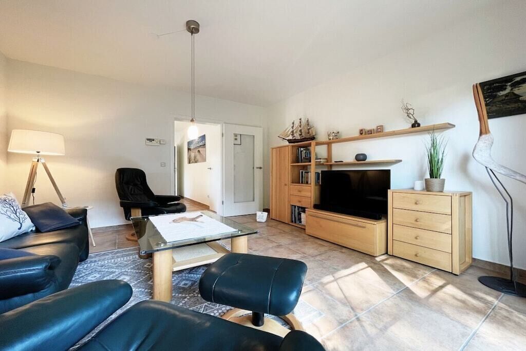 Ein modernes Wohnzimmer mit einer Couch, einem Couchtisch, einem TV-Schrank und einem Bücherregal.