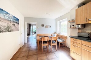 Eine Küche mit Holzausstattung, einem Esstisch mit Stühlen und einer Pendelleuchte.