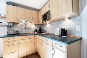 Eine Küche mit Holzschränken, einer Mikrowelle, einer Kaffeemaschine und einem Toaster.