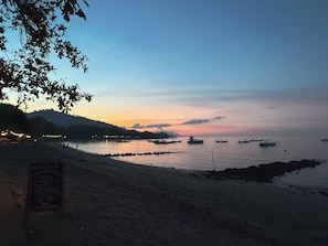 A beach with boats, a signboard, and a clear sky.