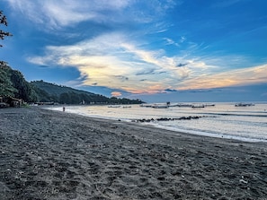 A beach with a clear sky, calm sea, and a distant shoreline.